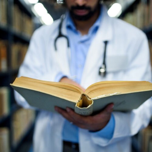 Unrecognizable doctor in library, studying information about corona virus. Learning Resources