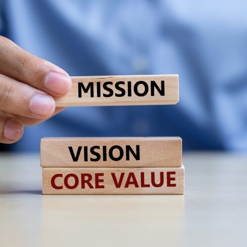 Businessman hand holding wooden building blocks on table backgro “Why Core Values Drive Success in Healthcare Businesses”